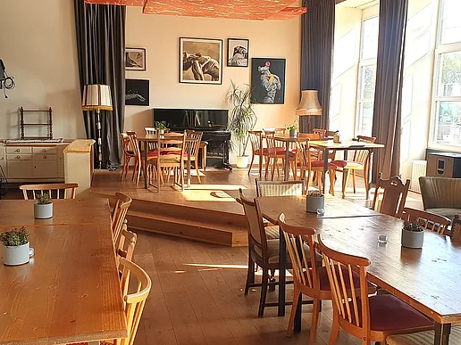 Die Bestuhlung und einige Tische in der Bar, im Hintergrund ist das Piano sichtbar