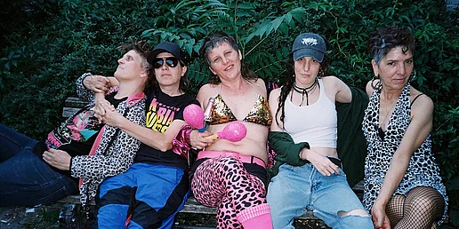 Die fünf MItglieder der Kumbia Queers sitzen auf einer Bank vor einer Palme