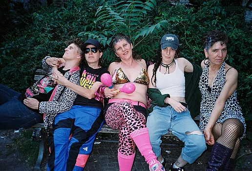 Die fünf MItglieder der Kumbia Queers sitzen auf einer Bank vor einer Palme