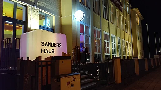 Die hell erleuchtete Front des Sandershauses in der Nacht